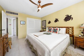 A bedroom with a bed, a ceiling fan, a dresser, a nightstand, and a wall with three turtle decorations.