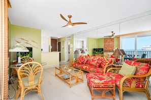 A living room with wicker furniture, a sofa with floral cushions, and a ceiling fan.