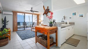 Een moderne keuken met een houten eiland, witte kasten en uitzicht naar buiten.