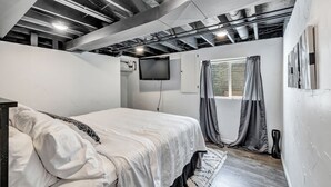 A bedroom with a bed, a TV, and a window with curtains. - Shadow Lane Tailgate House - Newly Remodeled (Green Bay)