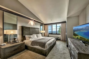 A modern hotel room with a large bed, a TV, and a view of a lake. - Constellation Residences at Northstar (Truckee)