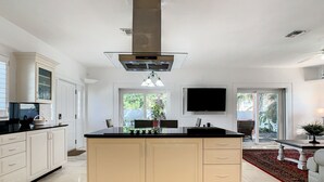 Una cocina moderna con una isla central, armarios blancos y una estufa grande.