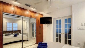 Un dormitorio con un espejo grande, una cama, un televisor y una puerta corrediza.