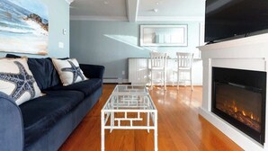 A living room with a sofa, a glass coffee table, a fireplace, and a TV. - Newport's favorite Neighborhood 3bed (Newport)
