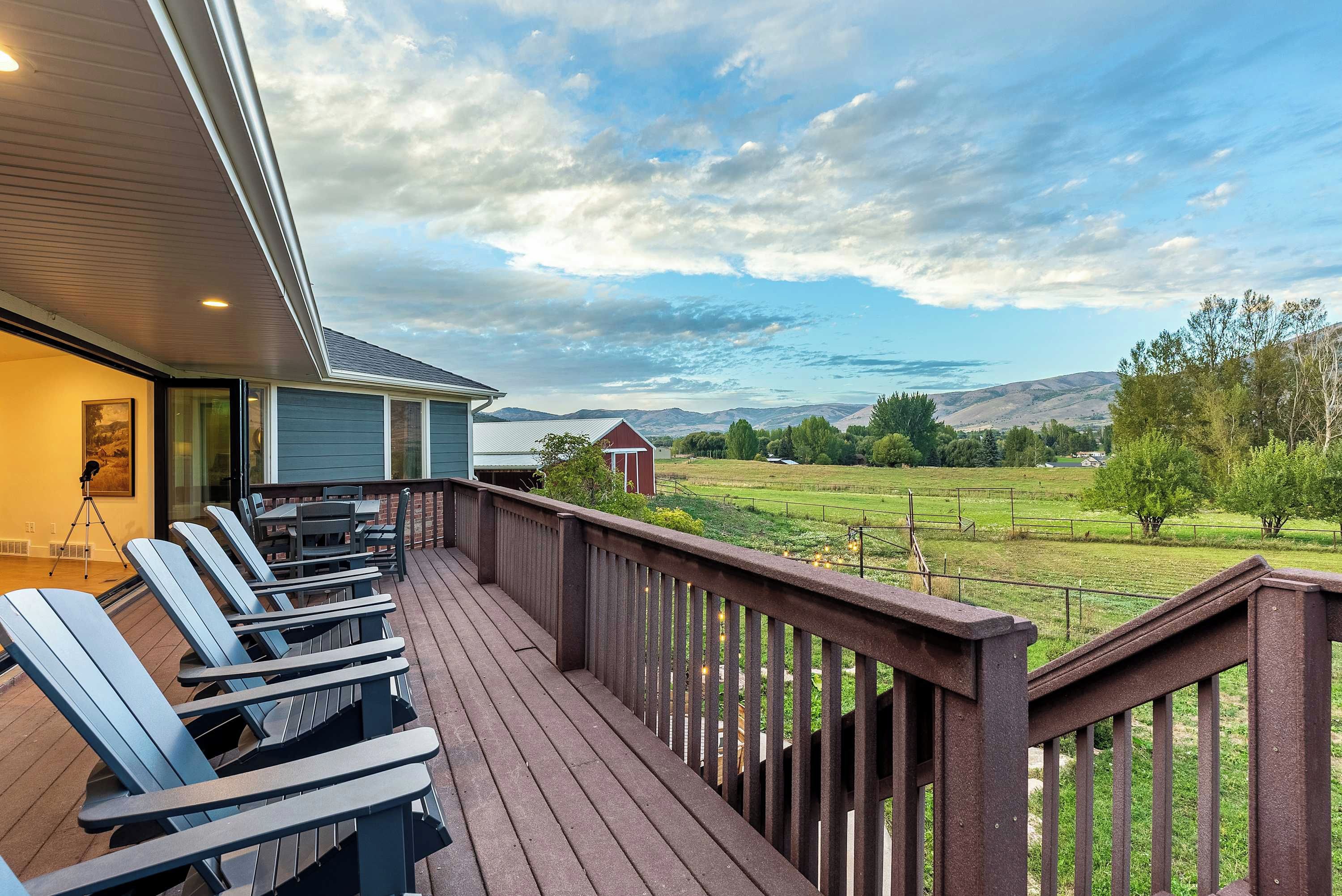 A deck with outdoor seating and a view of a rural landscape.