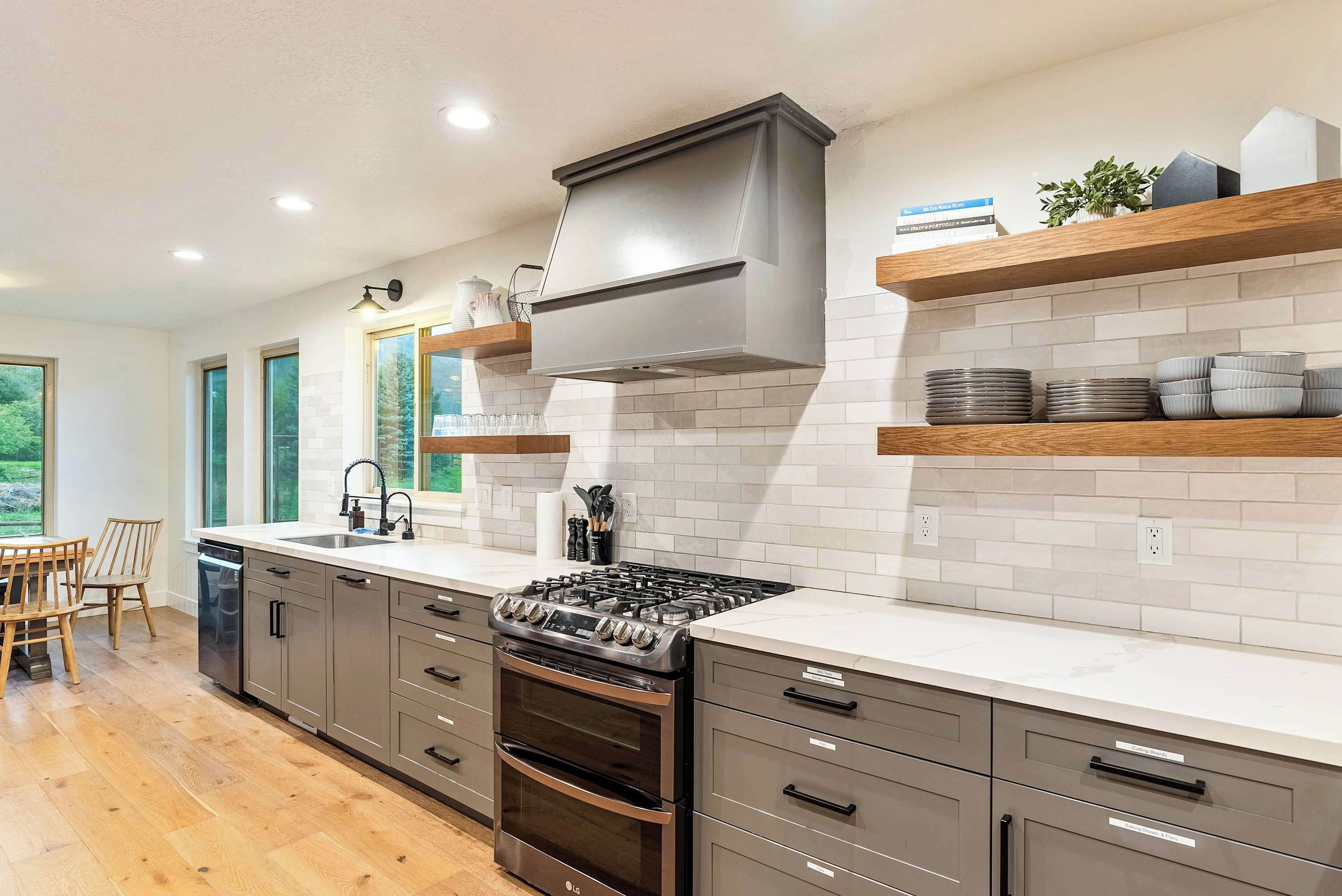 A modern kitchen with a built-in stove, oven, and a large window providing natural light.