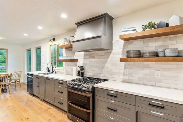 A modern kitchen with a built-in stove, oven, and a large window providing natural light.