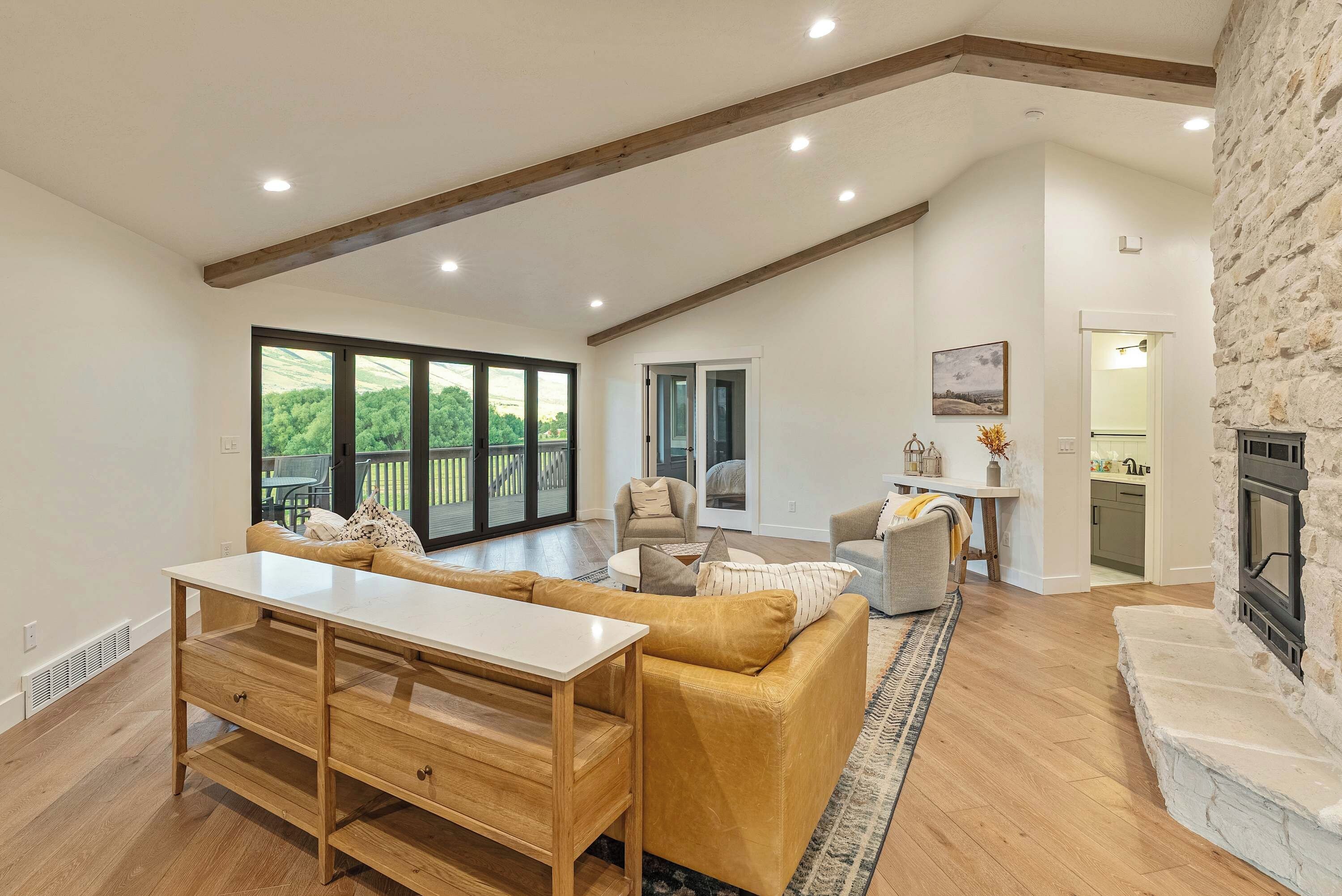 A spacious living room with a large window, a fireplace, and a kitchen area.