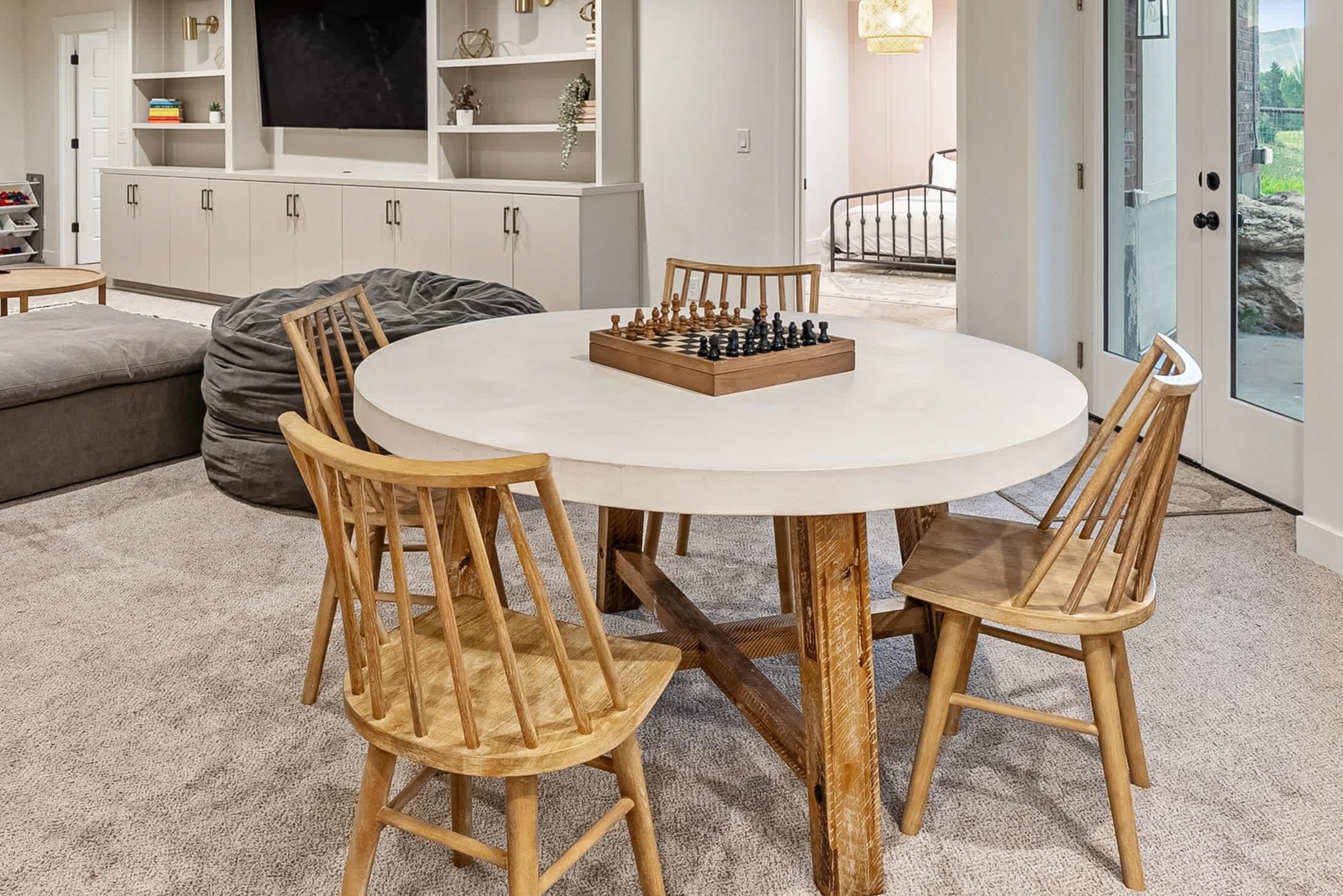 A round table with a chessboard in the center, surrounded by wooden chairs.