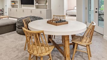 A round table with a chessboard in the center, surrounded by wooden chairs.