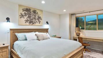A bedroom with a bed, bedside tables, a desk, and a window with a view.