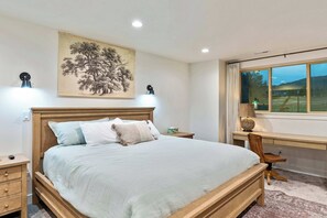 A bedroom with a bed, bedside tables, a desk, and a window with a view. - Horseshoe Haven (Eden)