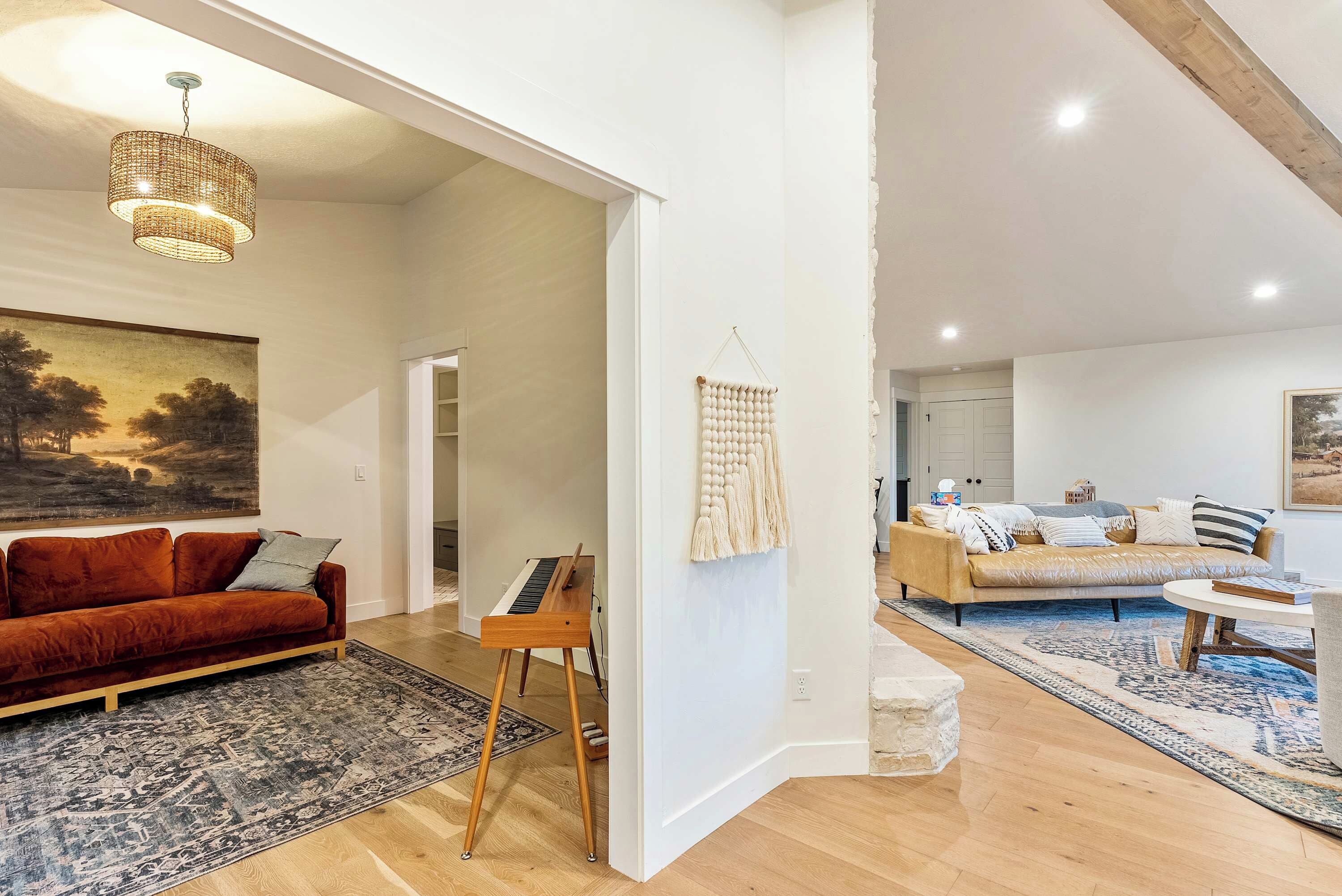 A spacious living room with a red sofa, a wooden music stand, and a macrame wall hanging.