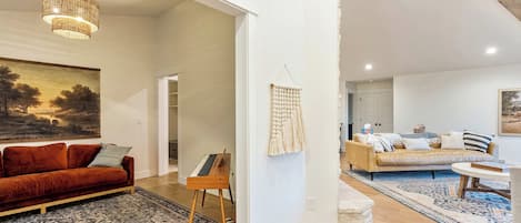Un salón amplio con un sofá rojo, un atril de madera y un tapiz de macramé.