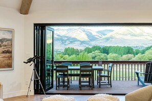 A room with a large sliding glass door leading to a deck with a mountain view.