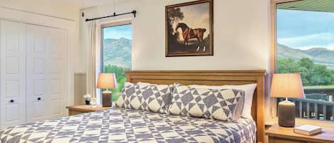 Un dormitorio con una cama grande, un cuadro de un caballo y vistas a las montañas a través de la ventana.