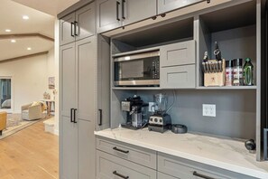 Una cocina con gabinetes grises, un microondas integrado, una licuadora y un bloque de cuchillos.