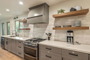 Una cocina moderna con estufa a gas, horno y cafetera sobre la encimera.