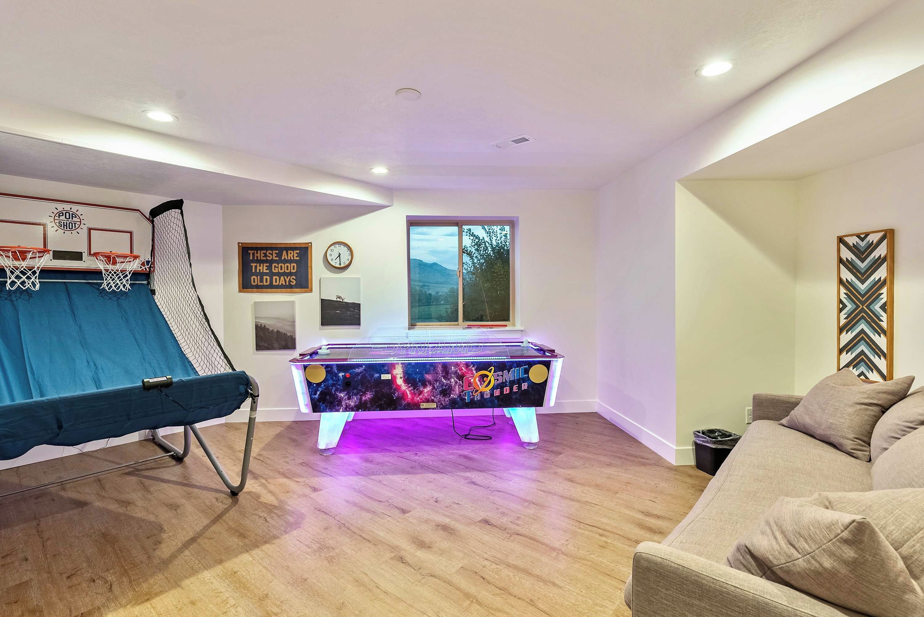 Una habitación con mesa de futbolín, aro de baloncesto y sofá.