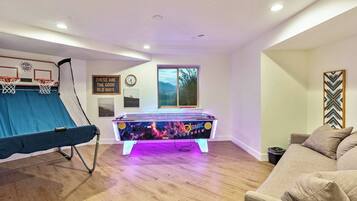 Una habitación con mesa de futbolín, aro de baloncesto y sofá.