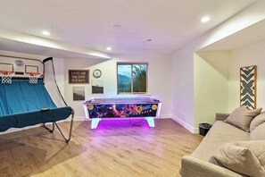 Una habitación con mesa de futbolín, aro de baloncesto y sofá.