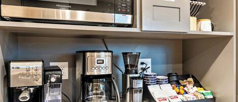 Eine Küchenzeile mit einer Frigidaire-Mikrowelle, einer Kaffeemaschine und einem Kaffeemühle.