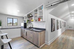 A modern kitchen with white cabinetry, a black countertop, and a window overlooking a cityscape.