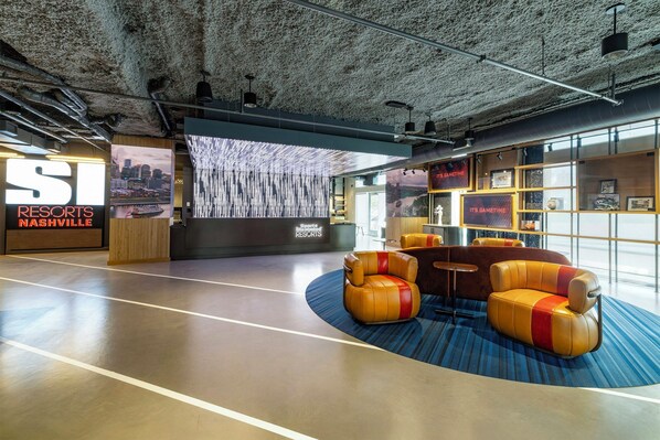 A modern lobby with a large digital display, seating area, and a Sports Illustrated Resorts sign. - Sports Illustrated Resorts Nashville (Nashville)
