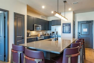 Una cocina moderna con una isla central, electrodomésticos de acero inoxidable y armarios oscuros.
