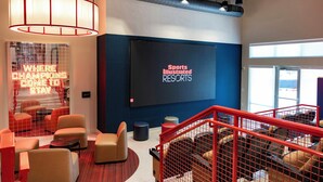 A modern hotel lobby with a large screen displaying 'Sports Illustrated Resorts' and a neon sign reading 'Where Champions Come To Stay.' - Sports Illustrated Resorts Nashville (Nashville)