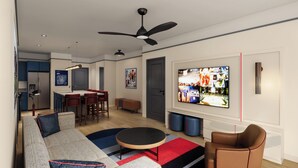 A modern living room with a sofa, coffee table, and TV. There is a kitchen area with a fridge and a dining table.