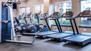 Une salle de sport équipée de tapis de course, de vélos elliptiques et de matériel de musculation.