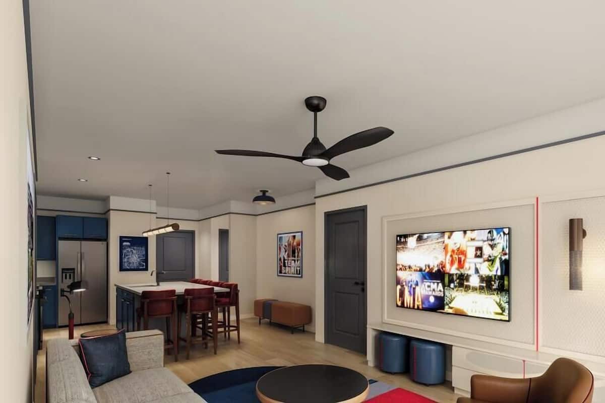 A modern living room with a ceiling fan, a TV, a dining area, and a kitchen.
