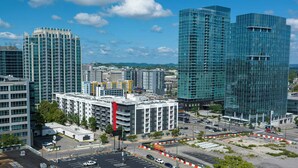 A high-rise building with a modern glass facade, surrounded by other buildings and a parking area. - Sports Illustrated Resorts Nashville (Nashville)