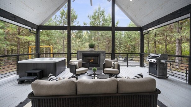 A covered outdoor deck with a fireplace, seating area, and grill. - Couples & Kids Barndominium Style Retreat (Broken Bow)