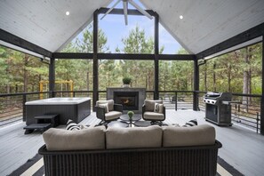 En overdækket terrasse med pejs, siddepladser og grill.