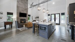 A spacious living area with a fireplace, a foosball table, and a large island with bar stools. - Couples & Kids Barndominium Style Retreat (Broken Bow)