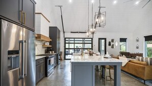 A spacious kitchen with a central island, stainless steel appliances, and a modern pendant light. - Couples & Kids Barndominium Style Retreat (Broken Bow)