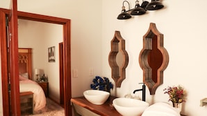 Une salle de bain avec un meuble-lavabo en bois, deux vasques blanches, un miroir et un porte-serviettes.
