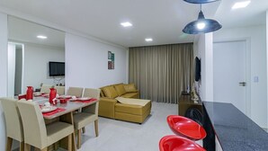 Un salon moderne comprenant un coin repas, un canapé et un téléviseur fixé au mur.