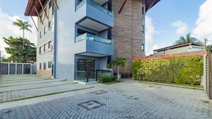 Un bâtiment moderne avec une façade recouverte de carreaux bleus, un balcon en verre et une cour dallée.
