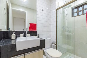 Ein modernes Badezimmer mit schwarzem Waschtisch, weißem Waschbecken und einer Duschkabine.