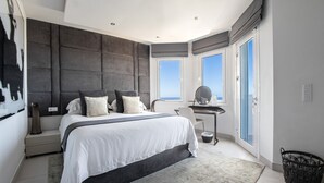 Una camera da letto moderna con un letto grande, una scrivania e vista sul cielo dalle finestre.