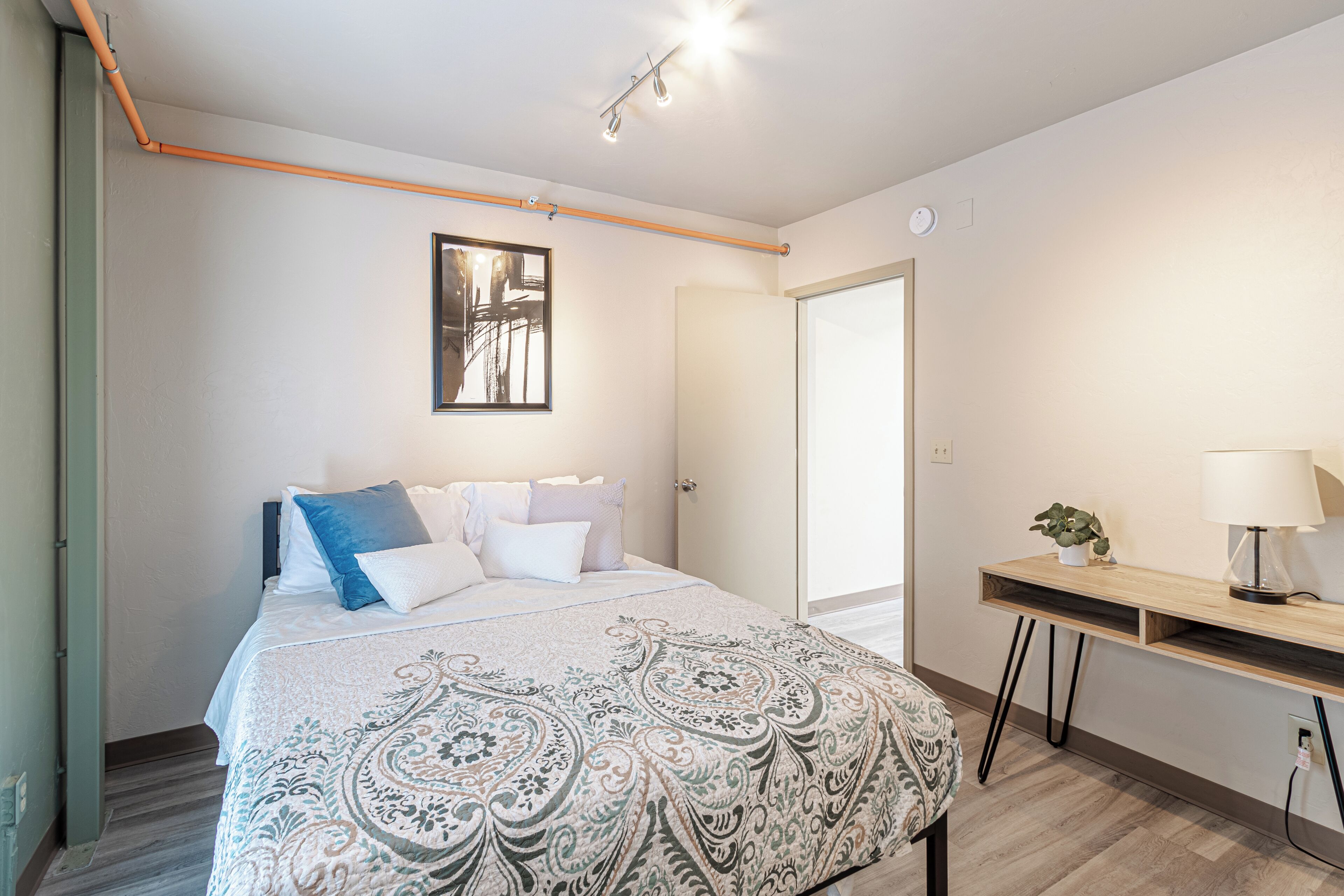 A bedroom with a bed, bedside table, lamp, and a door.
