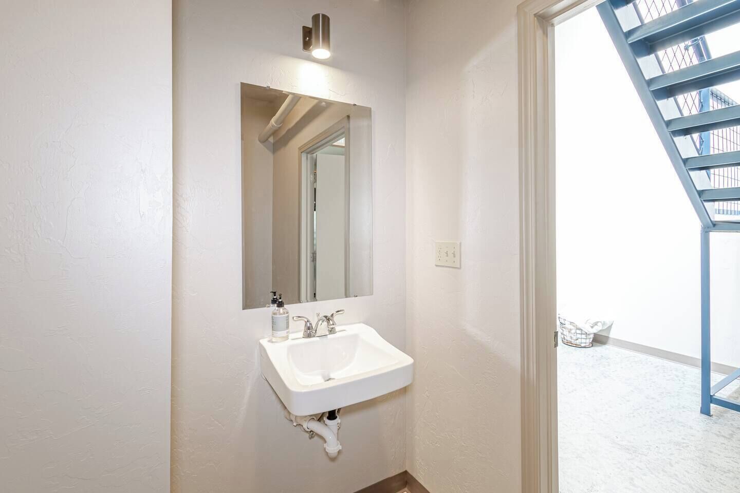 Un baño con un lavamanos blanco, un espejo y una lámpara.