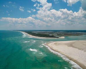 An aerial view of a coastal area with a sandy beach and clear blue waters. - Family beach cottage poised between the ocean, hiking, biking, eateries & shops (Emerald Isle)