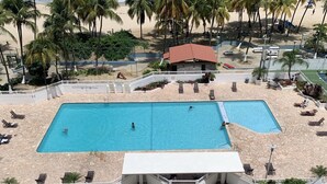Ein Poolbereich mit zwei Pools, umgeben von Palmen und Blick auf den Strand.