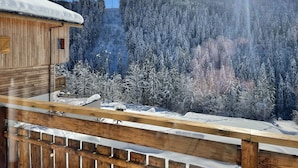 Une cabane en bois dotée d’un balcon enneigé qui offre une vue sur une région montagneuse couverte de forêts.