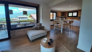 Un salon moderne avec un canapé, une table basse et de grandes fenêtres donnant sur une vue imprenable sur les montagnes.