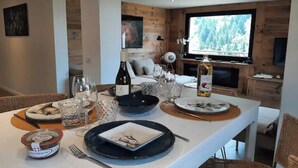 Un coin repas avec une table en bois mise pour le repas, un téléviseur et un espace salon confortable.